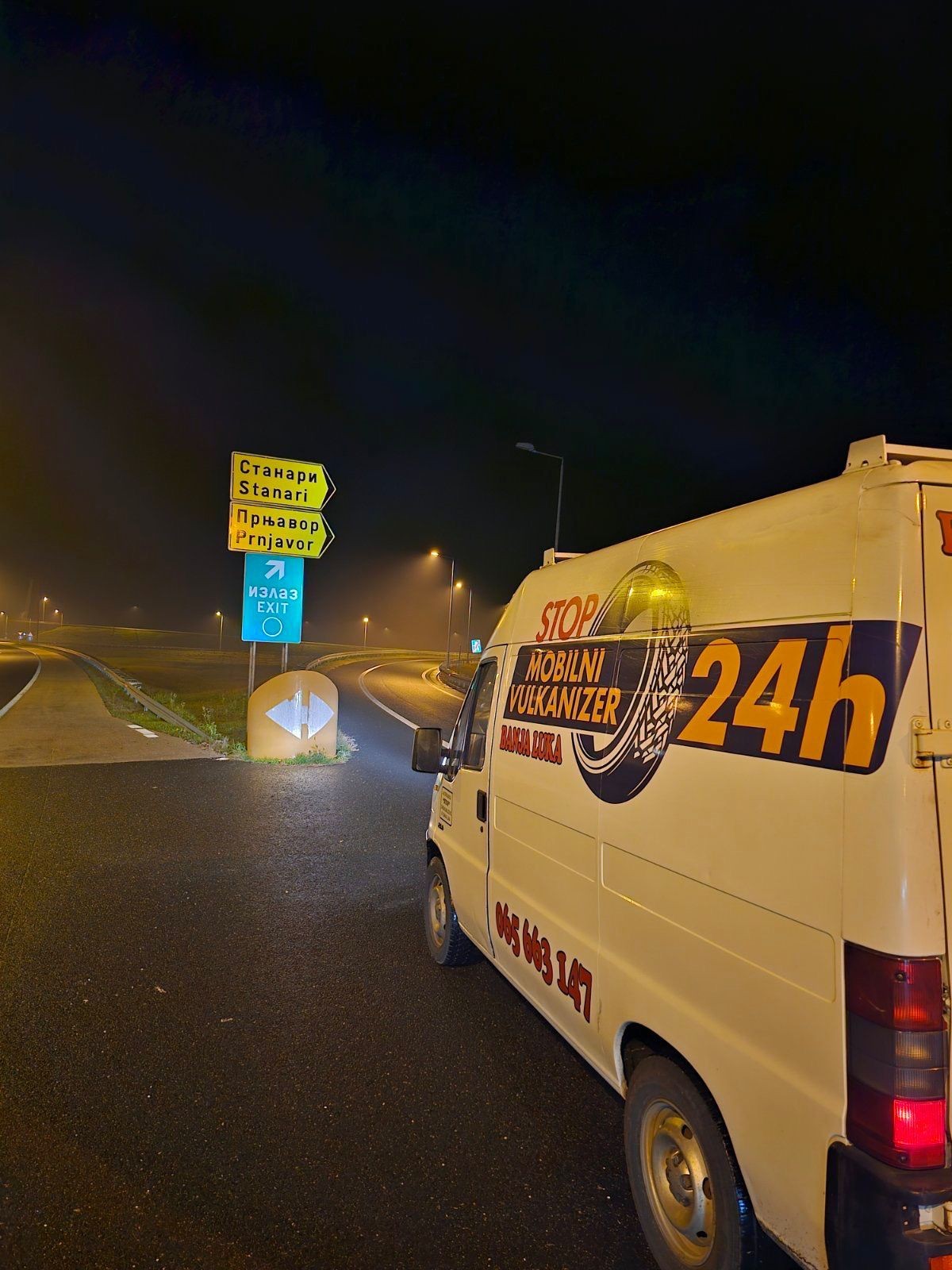 Mobile tire service van parked near highway exit sign for Stanari and Prnjavor at night.